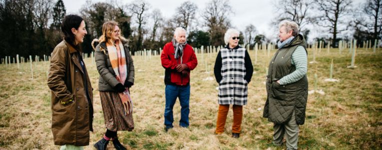 Group photo of 5 people talking in a newly planted woodland area. Photo credit Alex Turner Photography